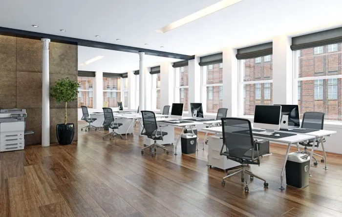 An empty office with wooden floors and lots of windows.