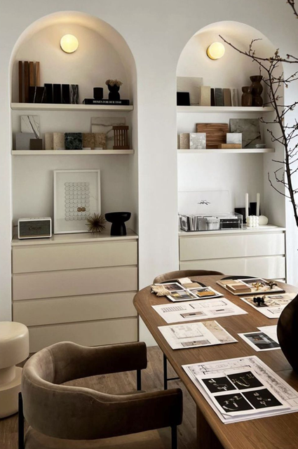 Dos nichos de pared blancos con arcos, estantes, iluminación tenue y elementos decorativos sobre cómodas minimalistas