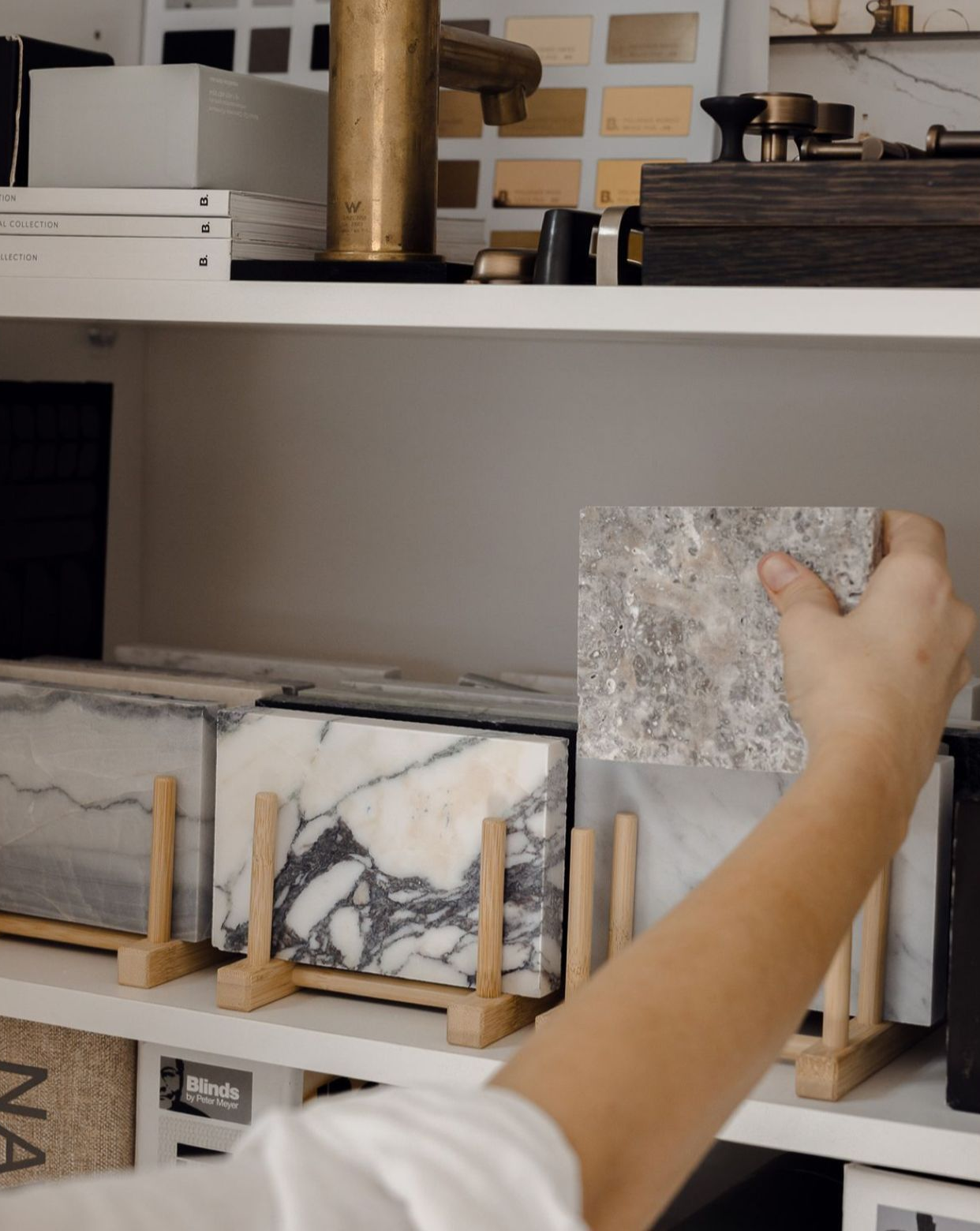 En un estudio de diseño, una persona sostiene una muestra de baldosa de piedra gris