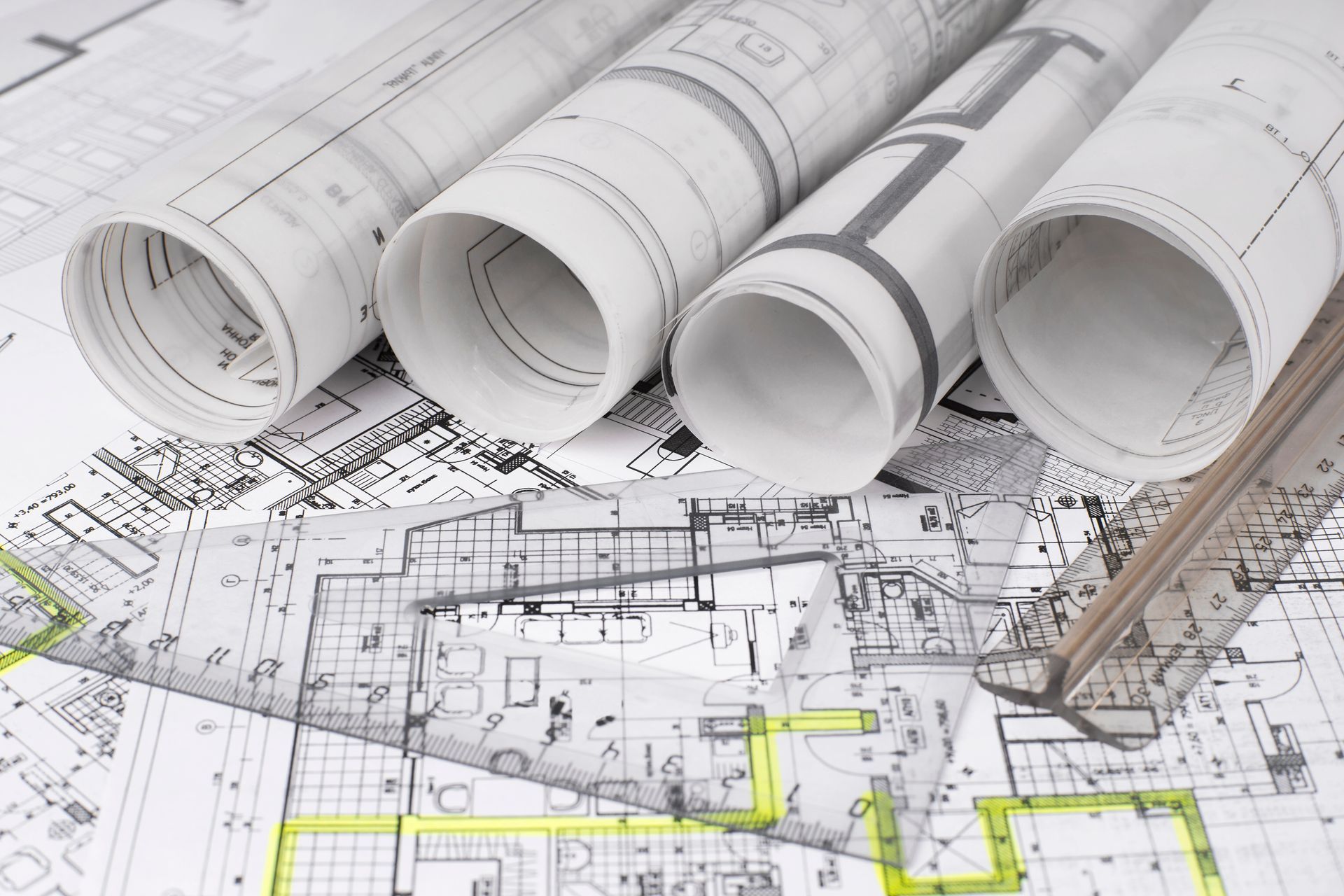 Planos arquitectónicos enrollados y planos de planta abierta, que muestran detalles de diseño y distribución.