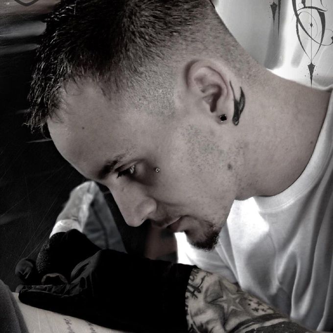A man is getting a tattoo on his arm
