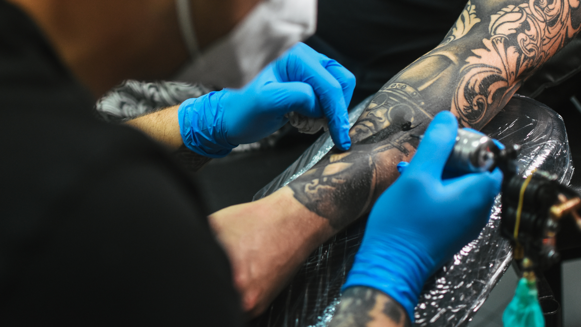 A man is getting a tattoo on his arm.