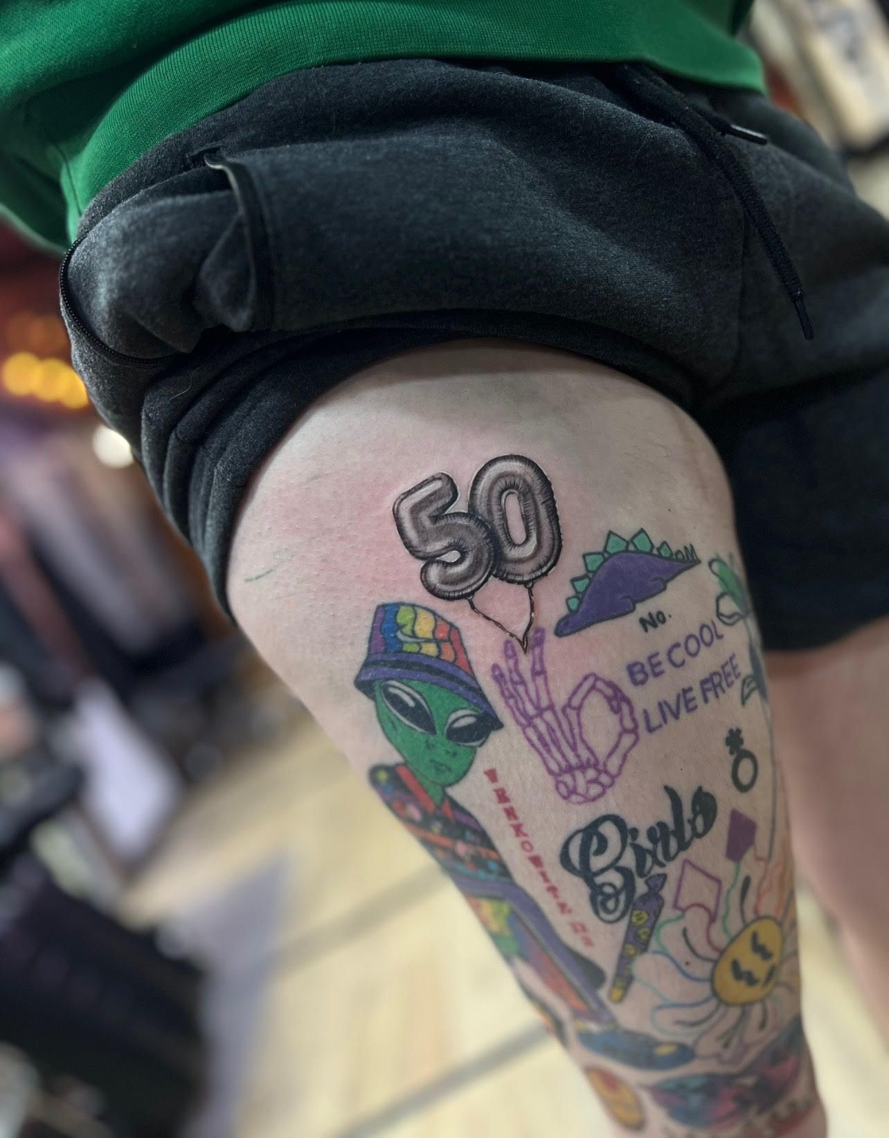 A person has a tattoo on their leg that says be cool live free