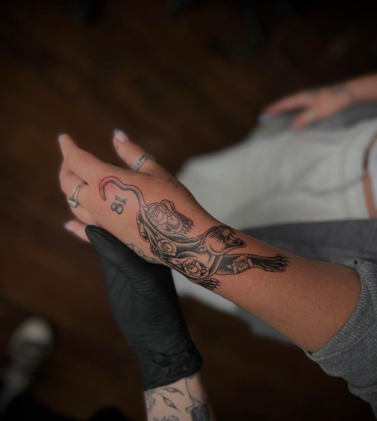 A woman has a tattoo of a cat on her wrist.