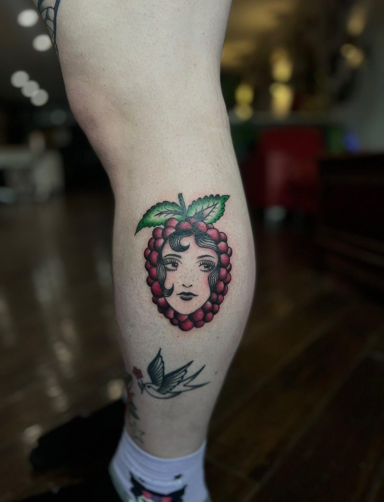 A woman has a raspberry tattoo on her leg