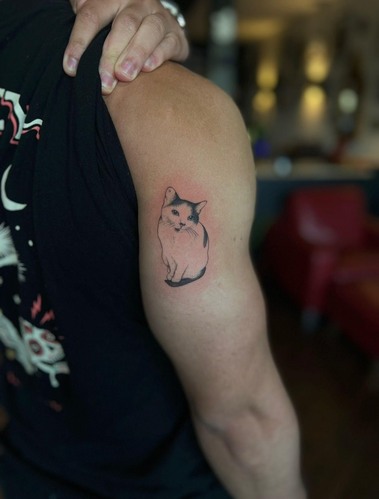A person has a tattoo of a cat on their arm
