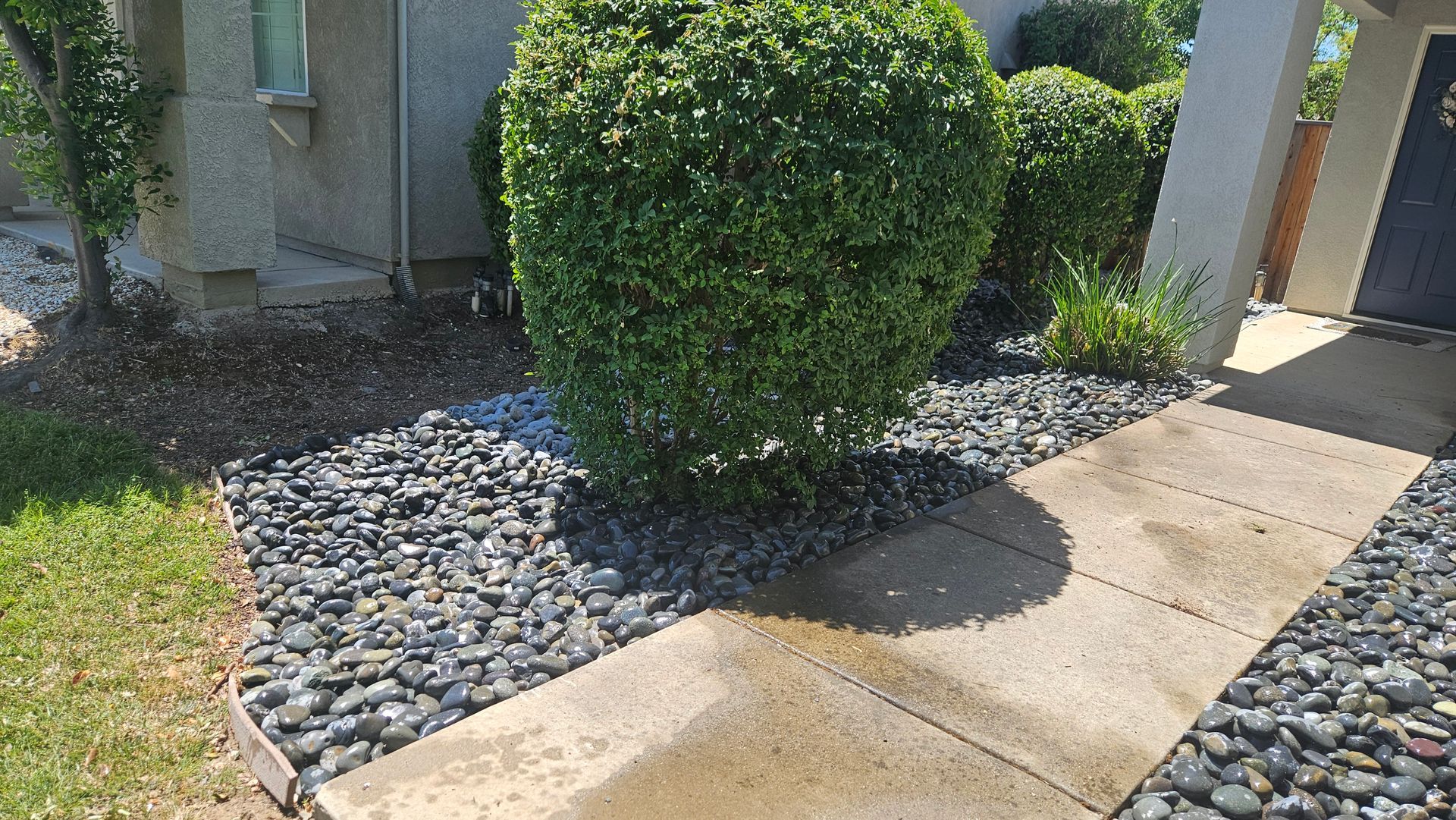Outdoor kitchen with stone walls, stainless steel appliances, and a grill.