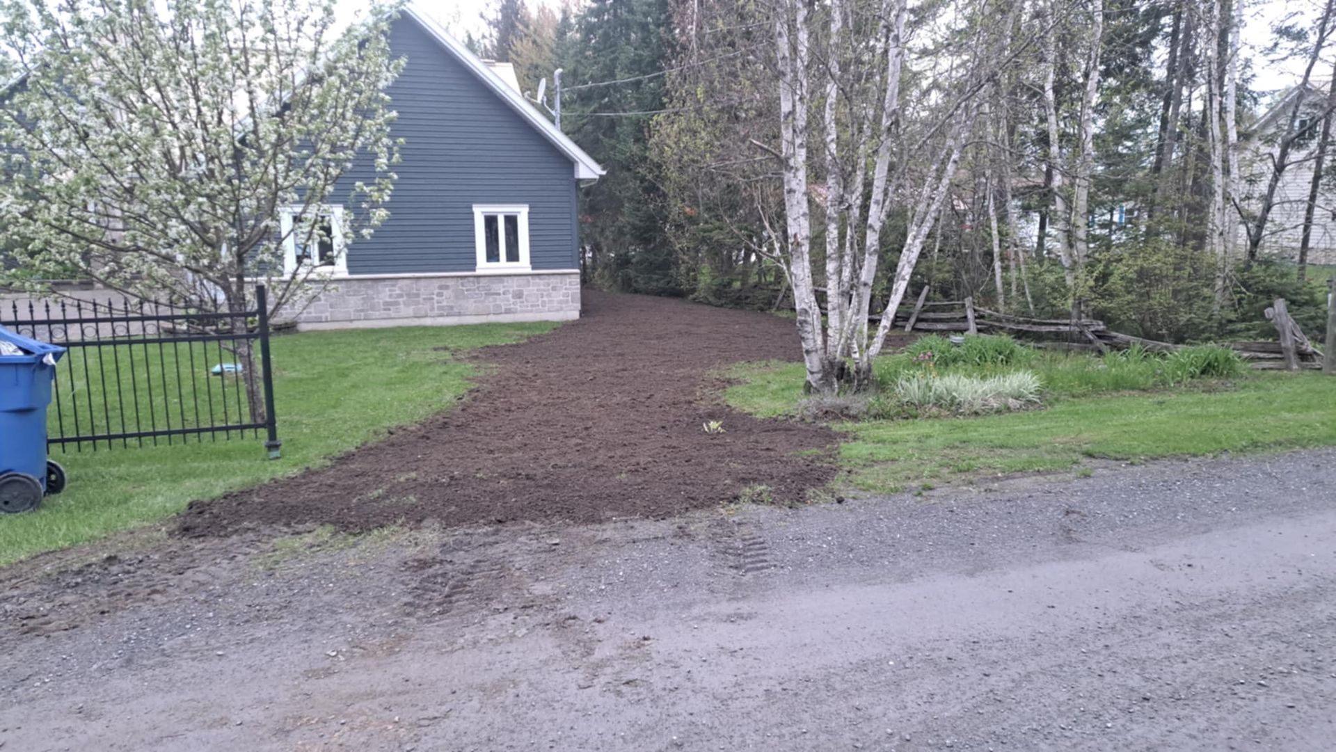 Une maison avec une poubelle bleue devant