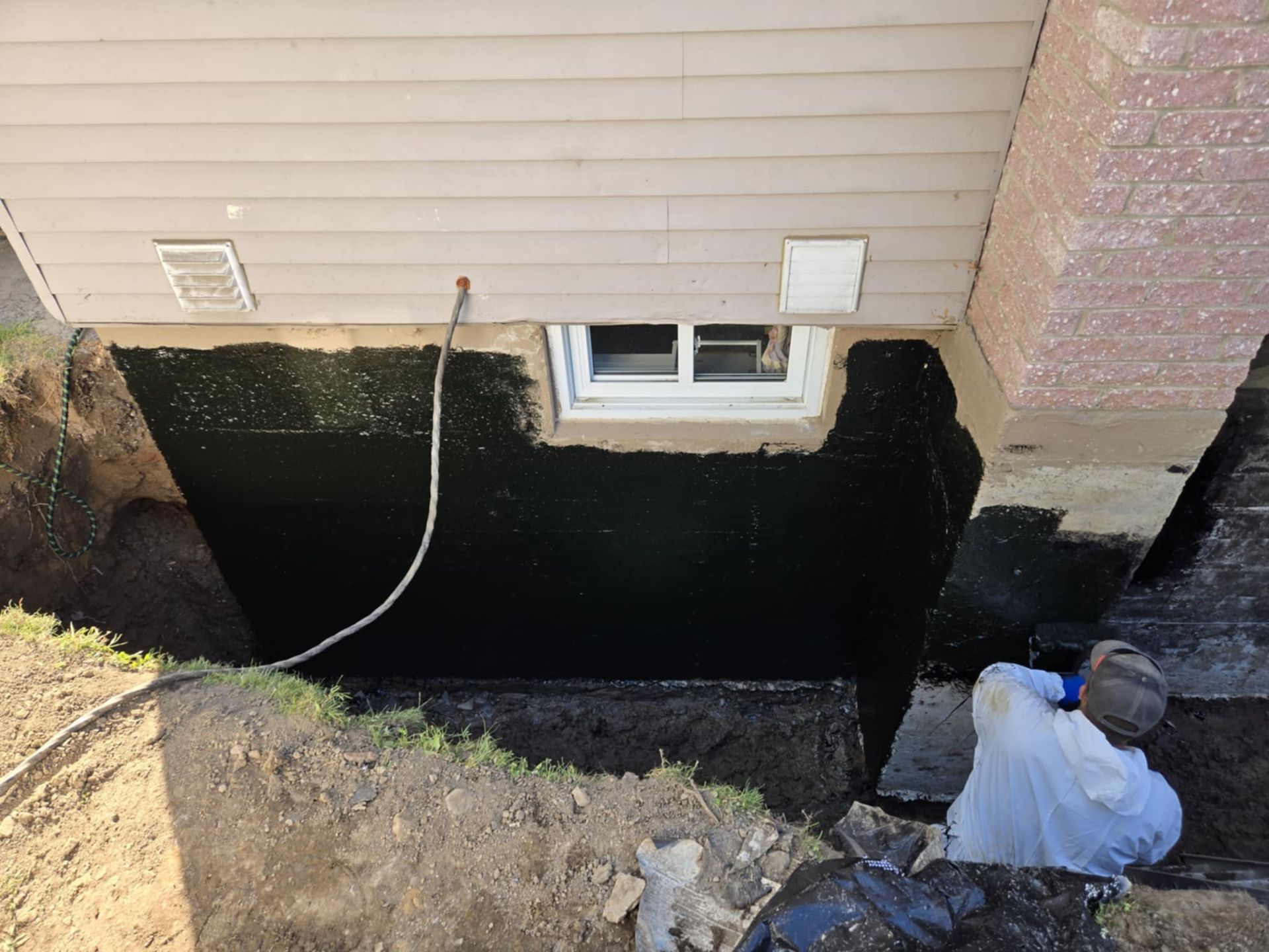 Un homme se tient dans un trou à côté d'une maison.