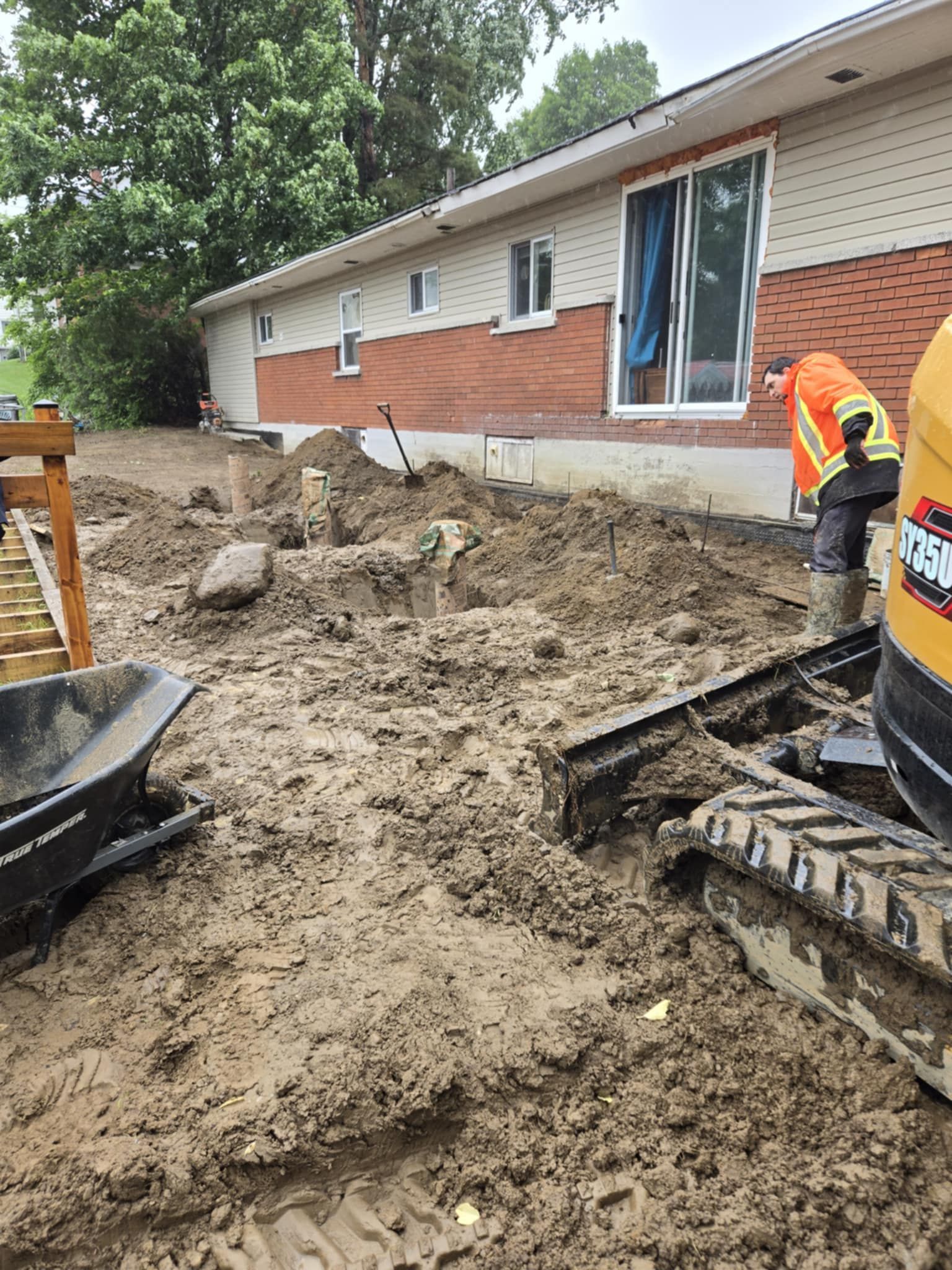 Un homme creuse dans la terre devant une maison.