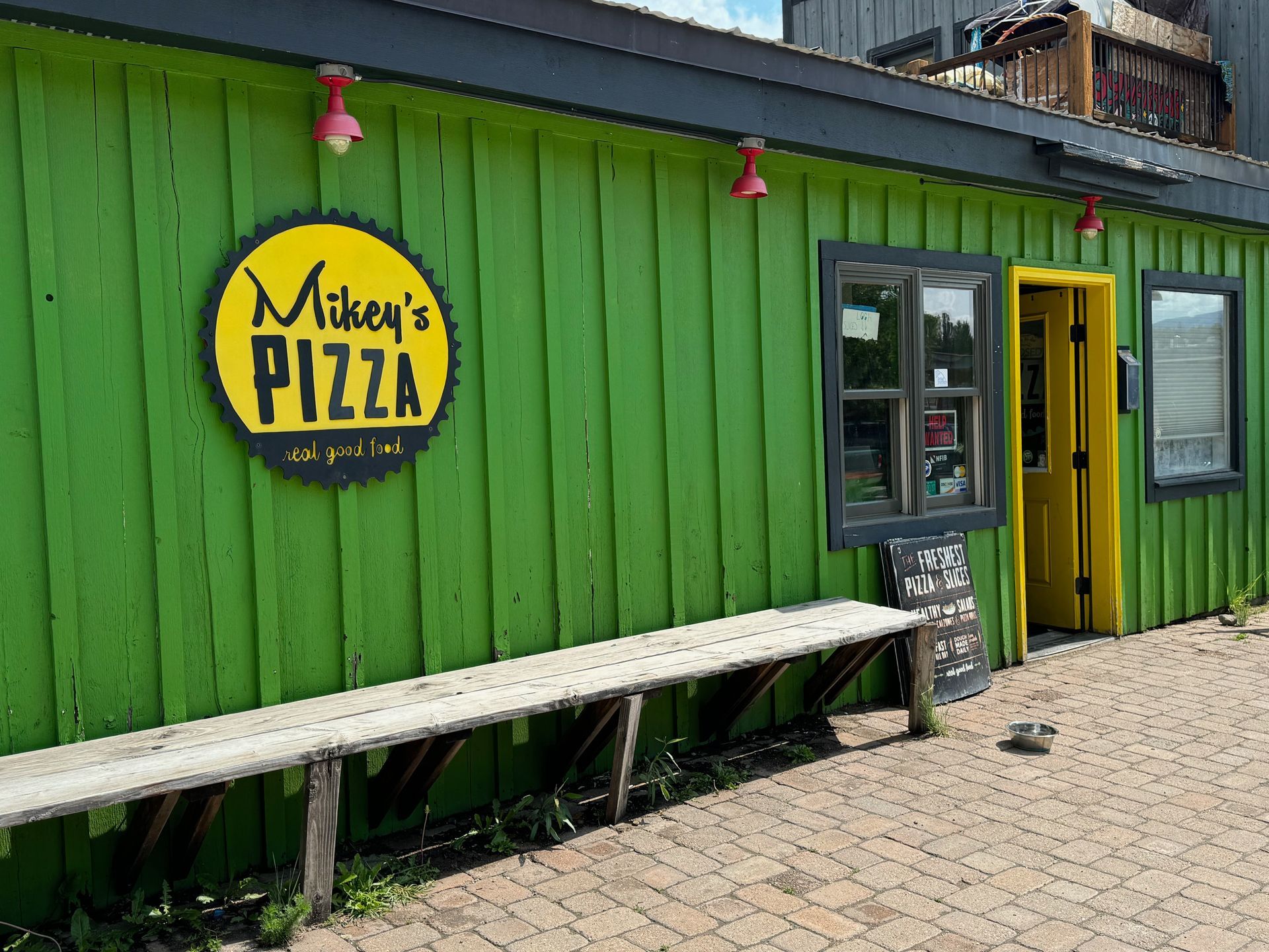 A green building with a yellow sign that says mike 's pizza on it.