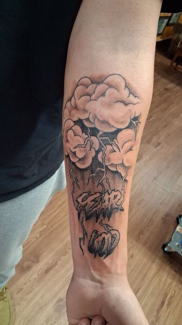 Tattoo of a floral bouquet with a butterfly on a forearm. Black line art.