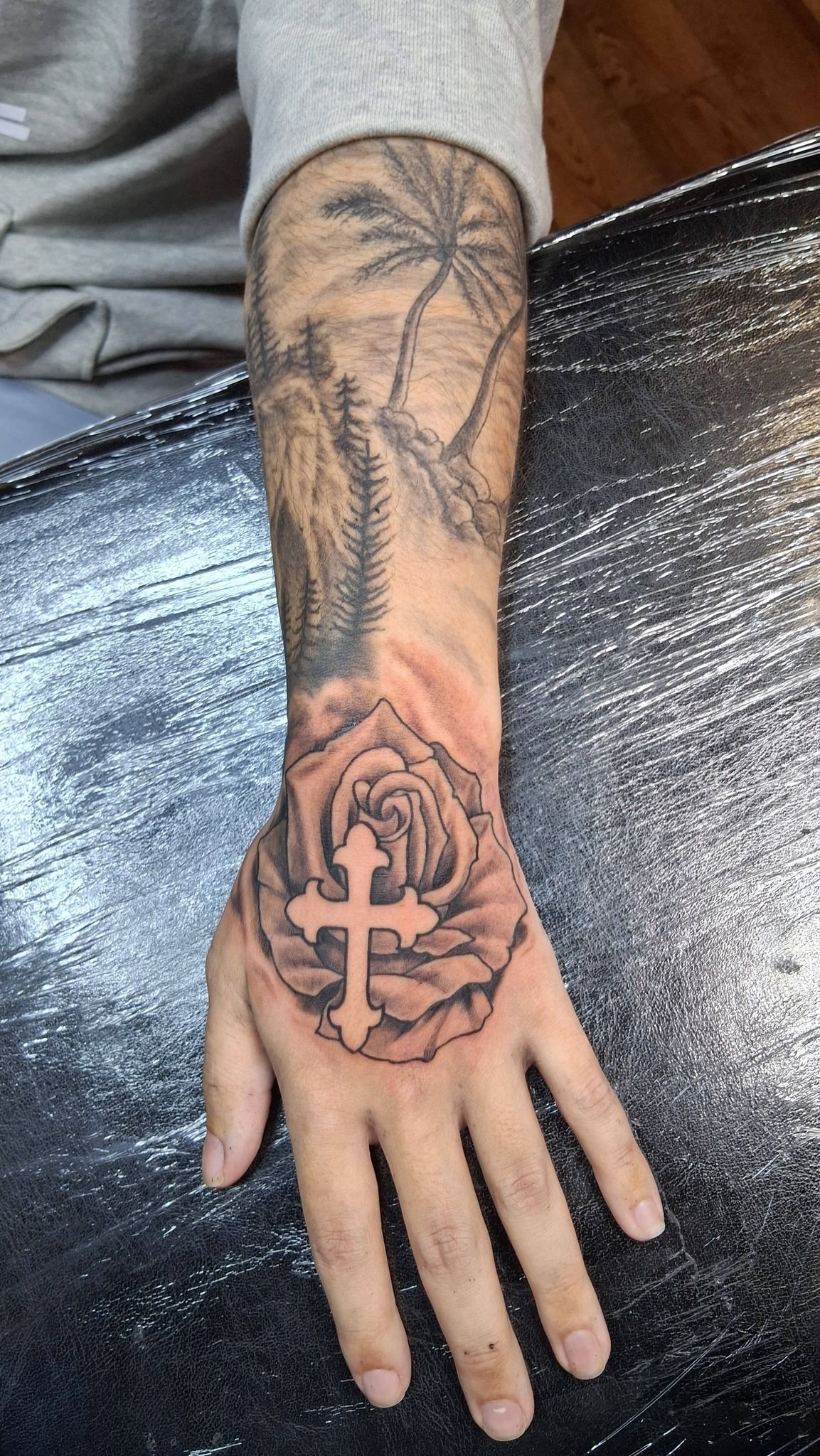 Tattoo of a compass rose atop an anchor, with rope detailing; grayscale on an arm.