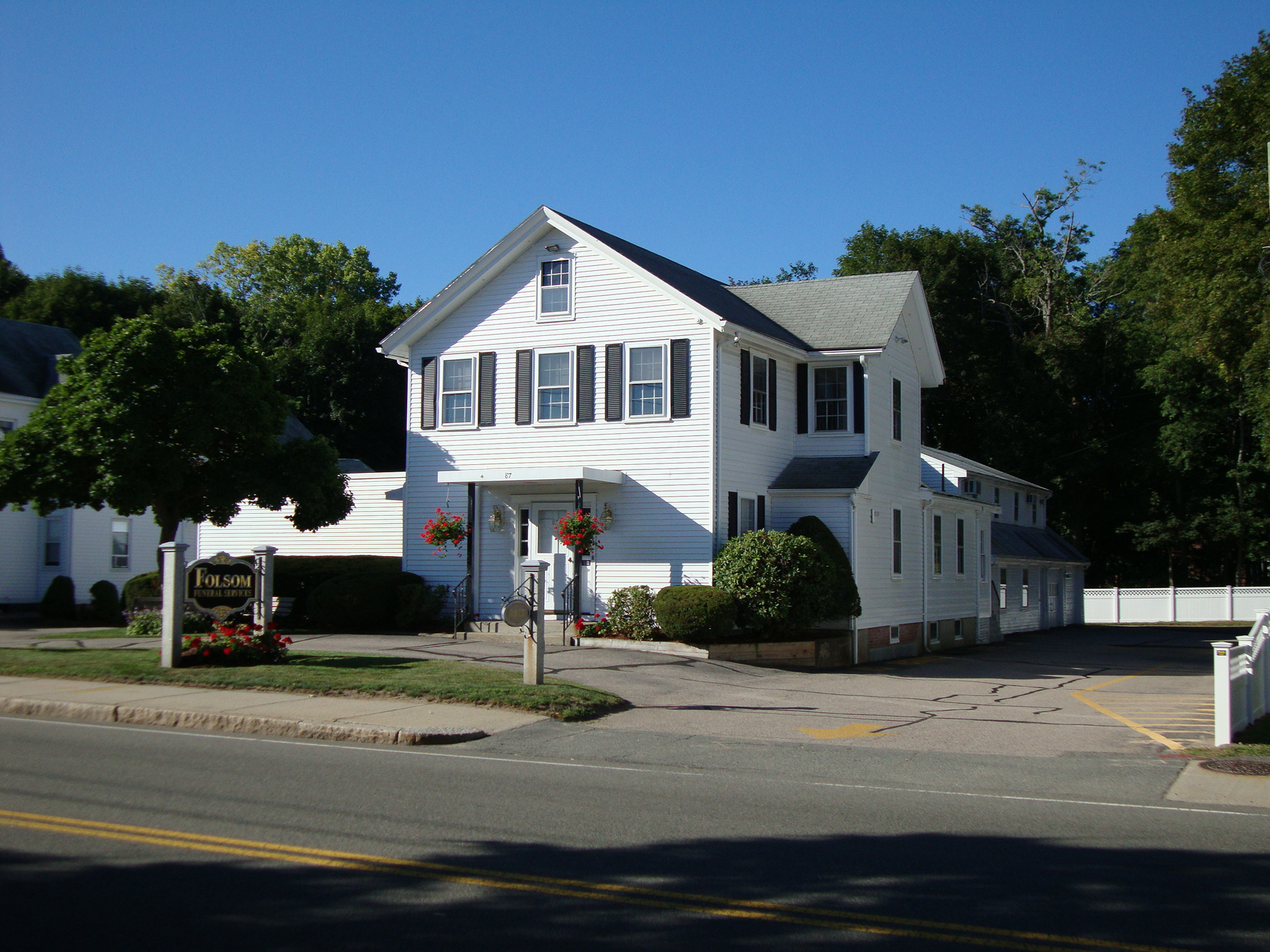 A large white house sits on the corner of a street