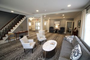 A living room with a couch , chairs , coffee table and stairs.