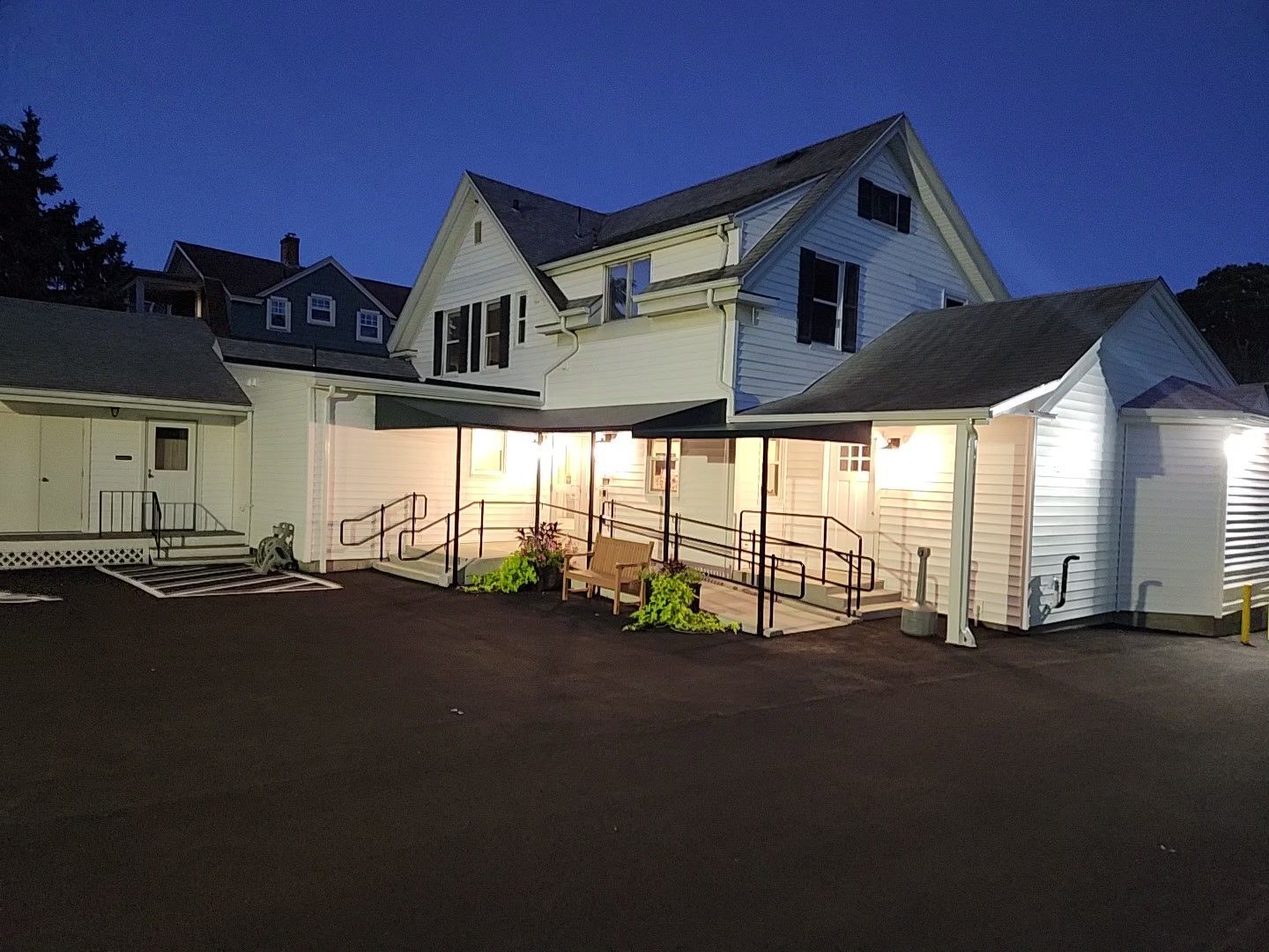 A large white house with a handicap ramp is lit up at night.