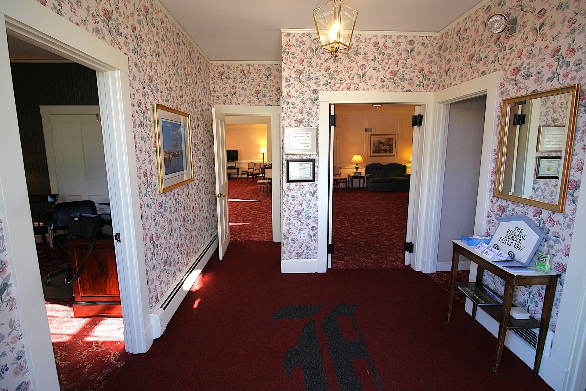 A hallway with a red carpet and floral wallpaper