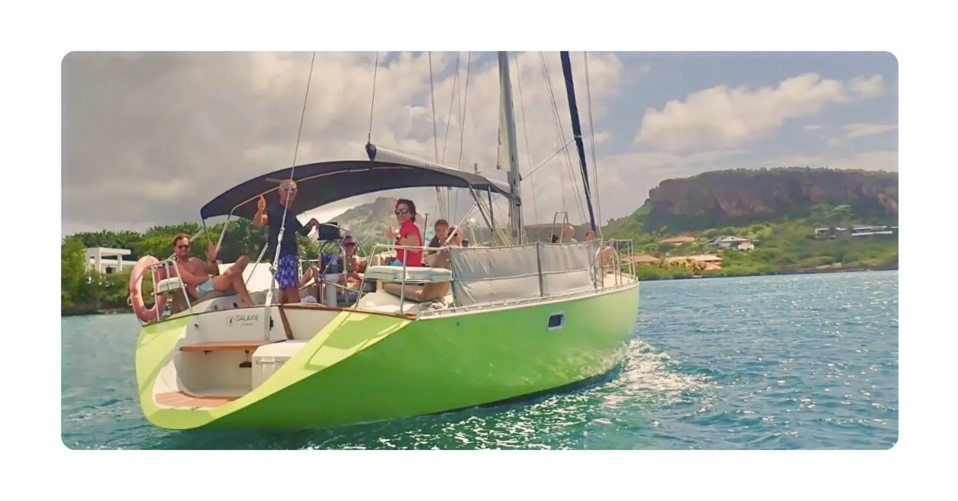 green sailing yacht Galaxie in Spanish Waters with Captain Norbert and Co-captain Hilde waving