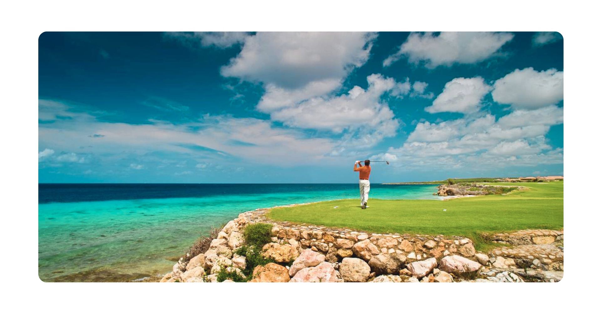 Golfer teeing off on a green of Old Quarry Golf Curacao, Caribbean Sea and blue sky in background.
