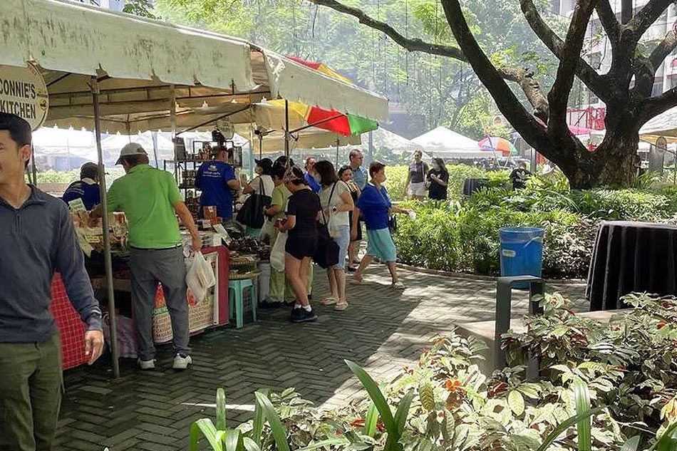 Guests browsing weekend market under shaded canopy near Makati boutique hotel garden