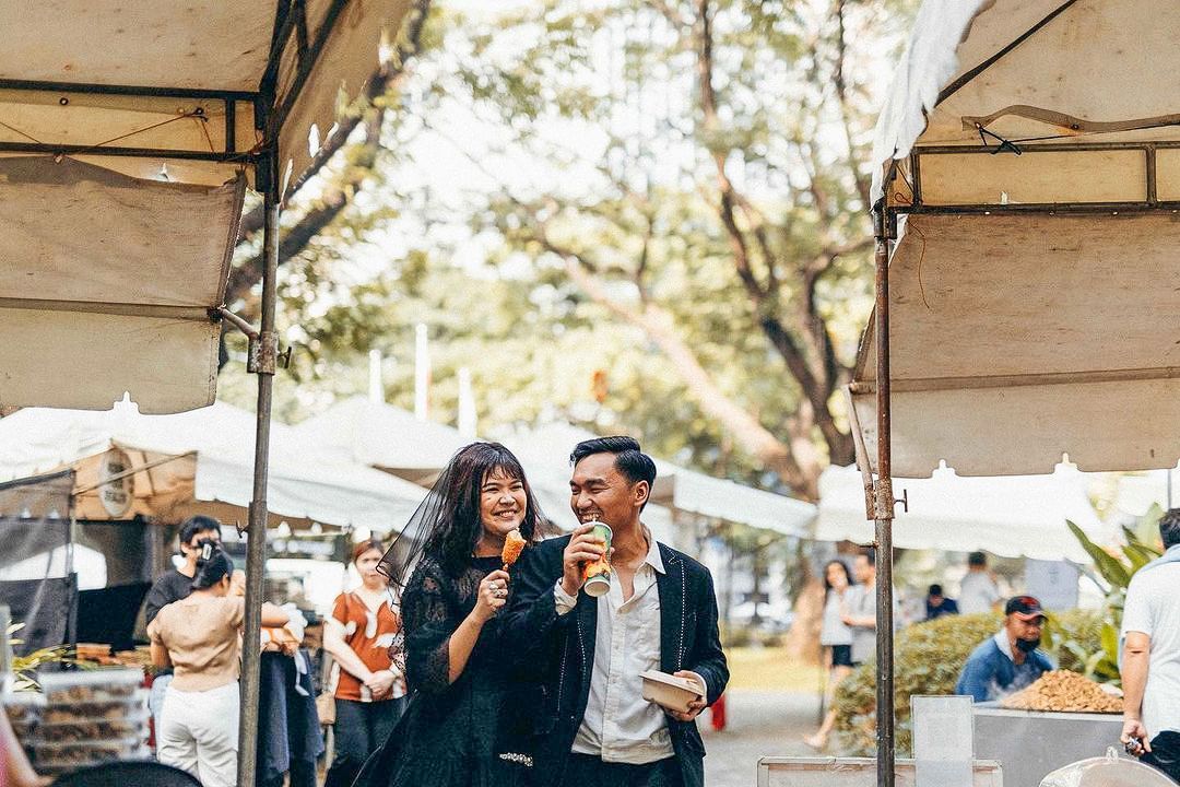 A man and a woman are eating ice cream at a market.