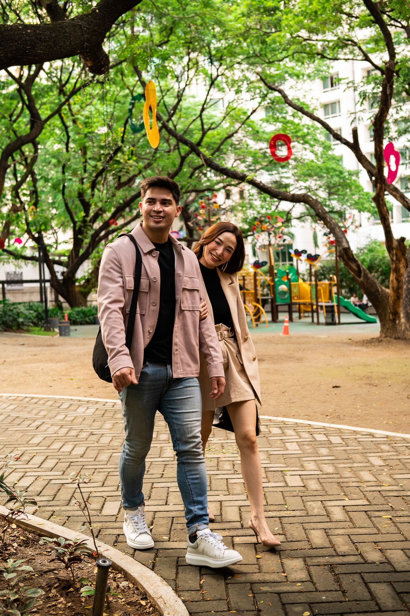 A man and a woman are standing next to each other in a park in Salcedo Village near The Picasso