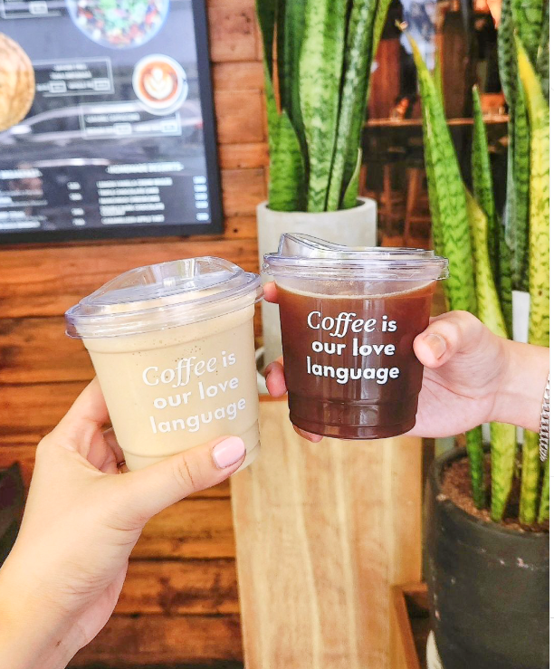 Two people are holding cups of coffee from Cartel Deli at Picasso Boutique Hotel in Makati