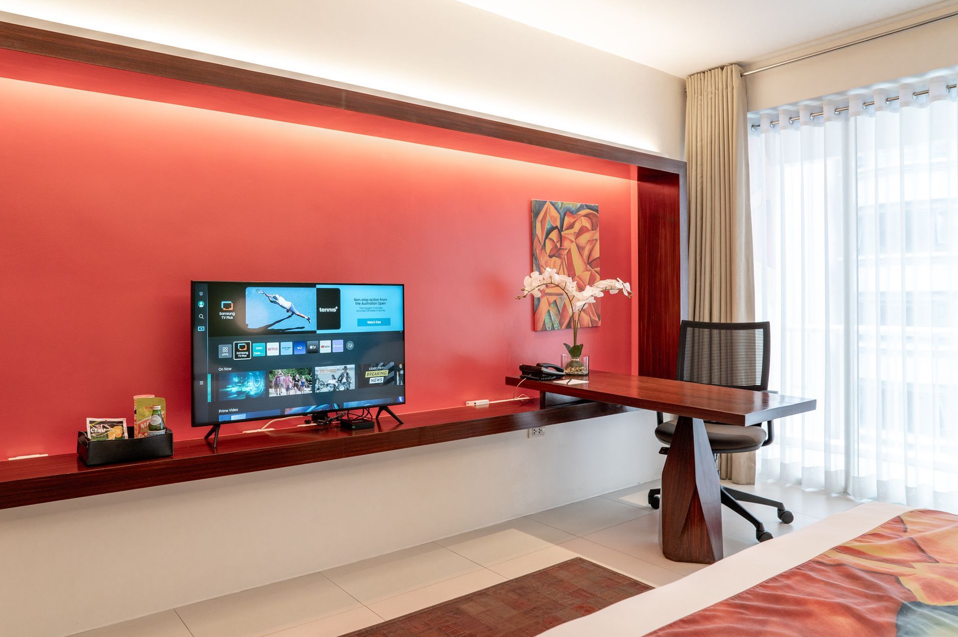 A hotel room with a desk and a flat screen tv