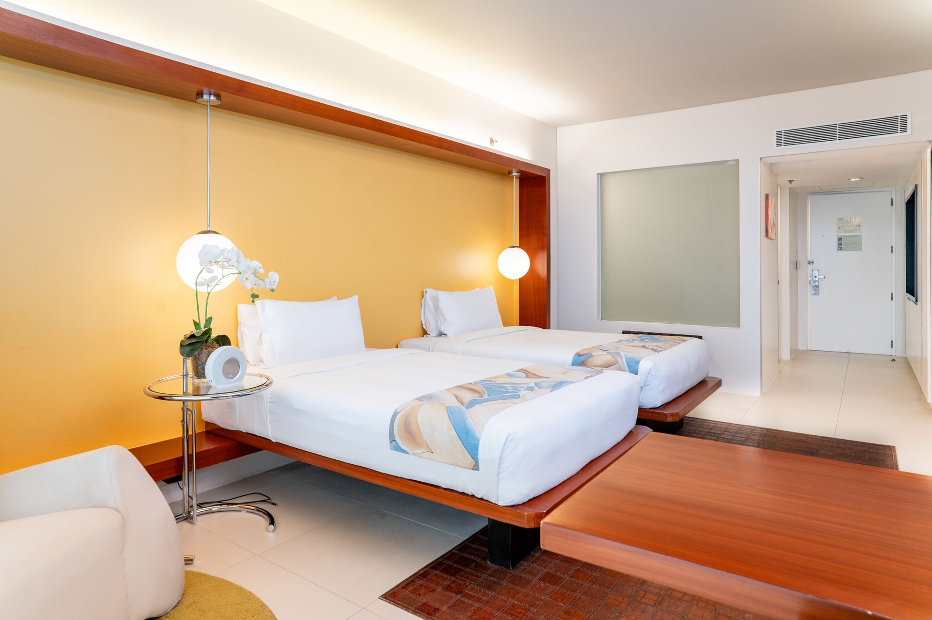 A hotel room with two beds and a yellow wall