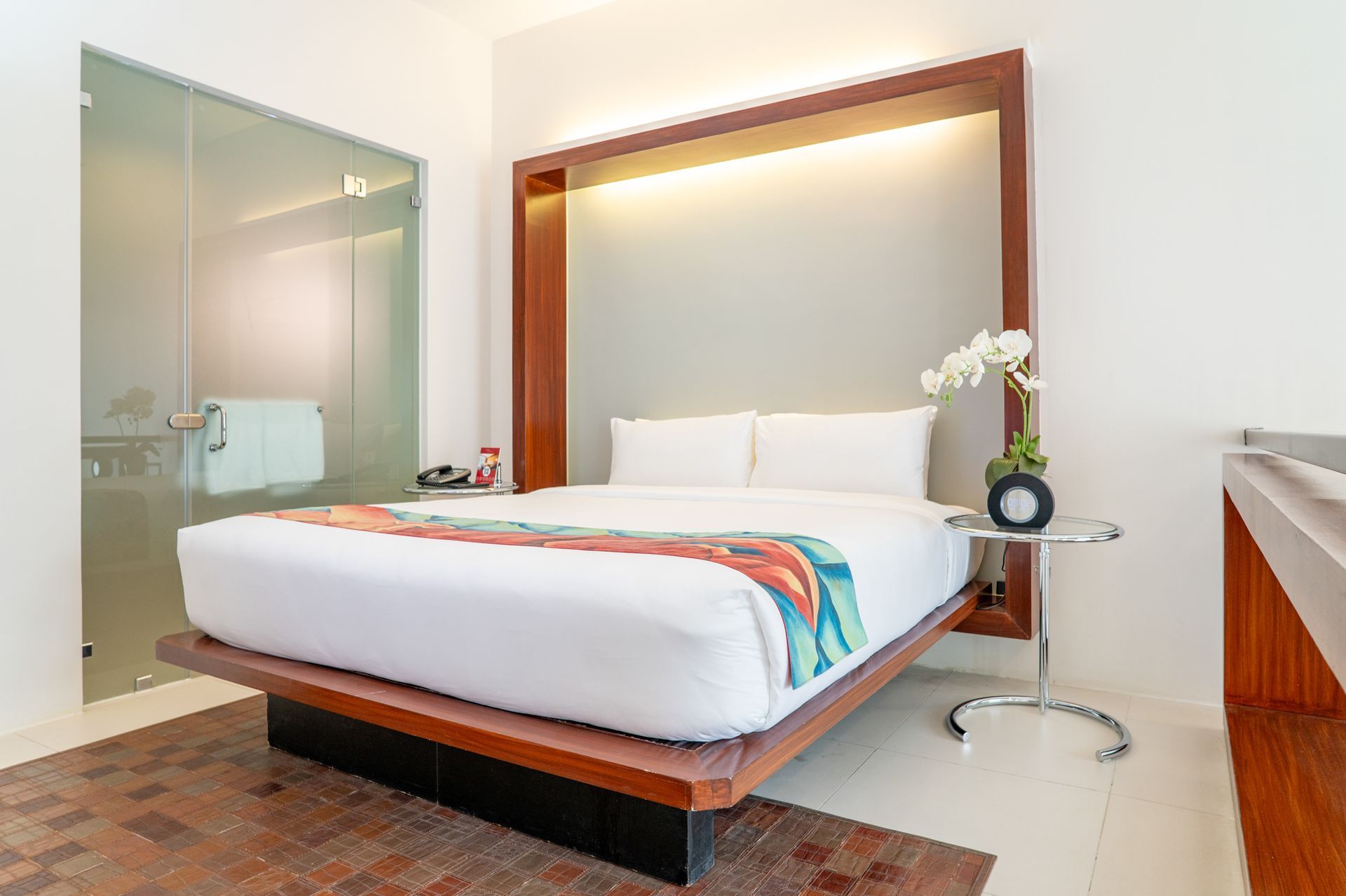 A hotel room with a large bed and a glass shower