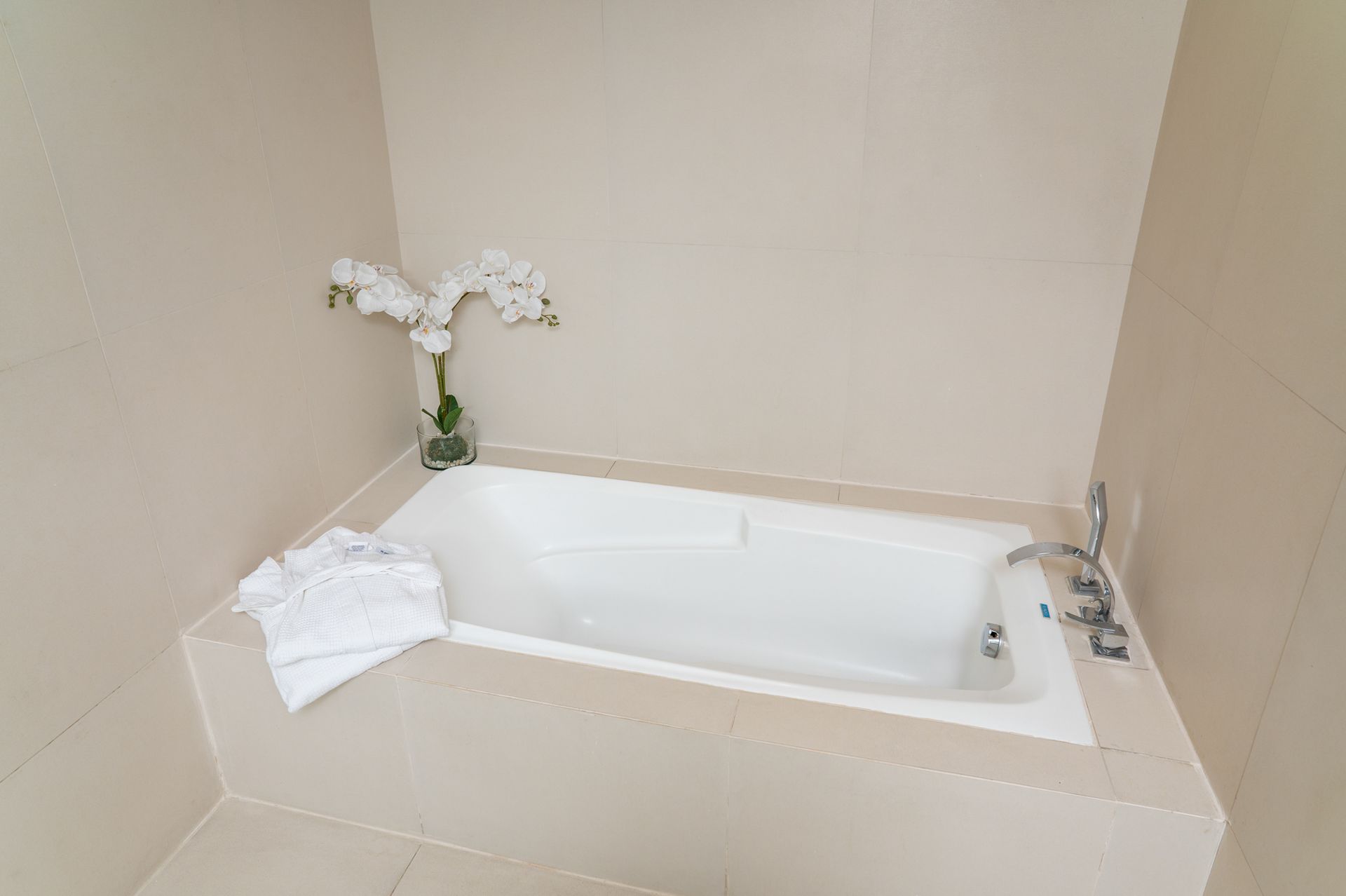 A bathtub in a bathroom with a vase of flowers on the side