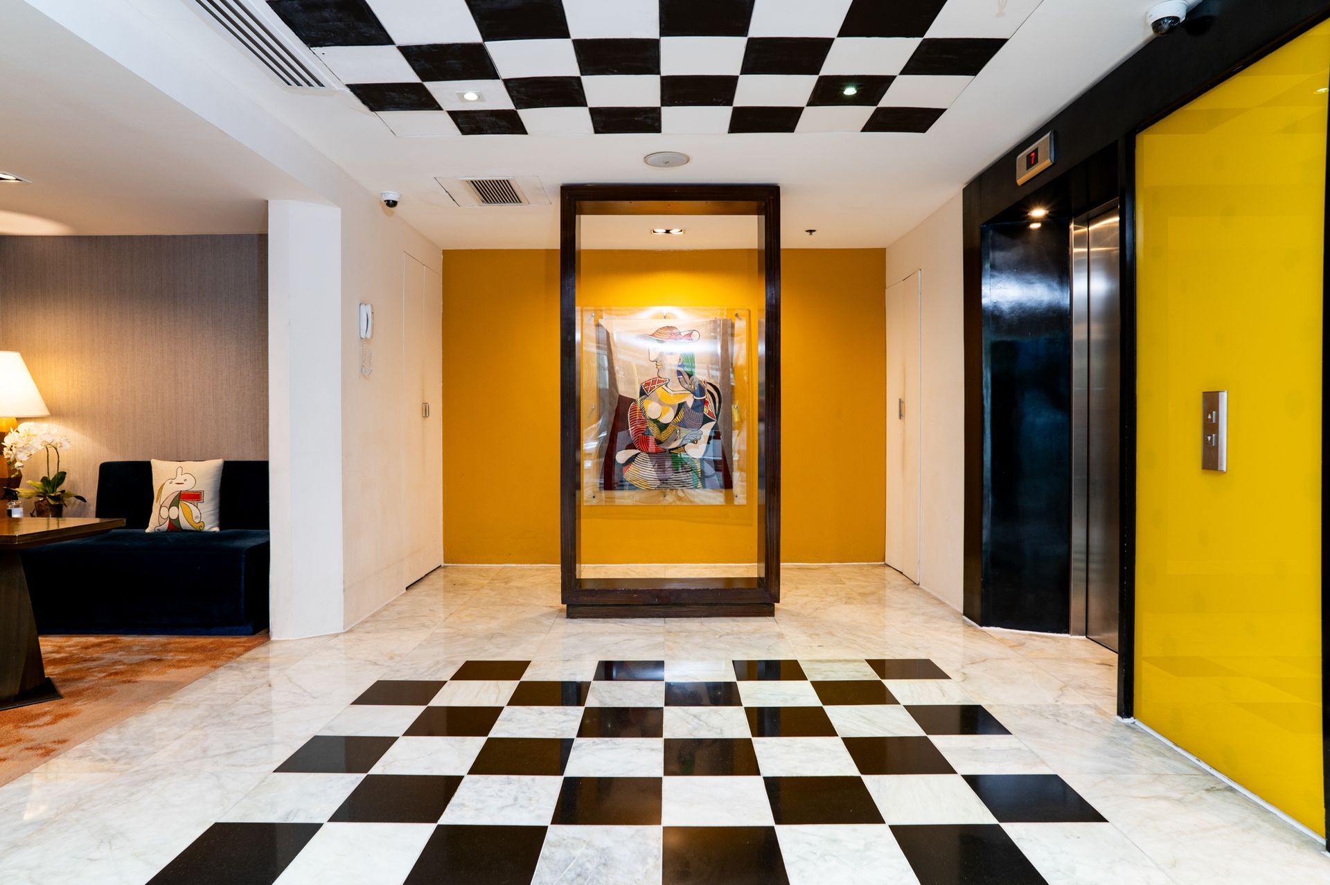 A hallway with a checkered floor and a yellow door