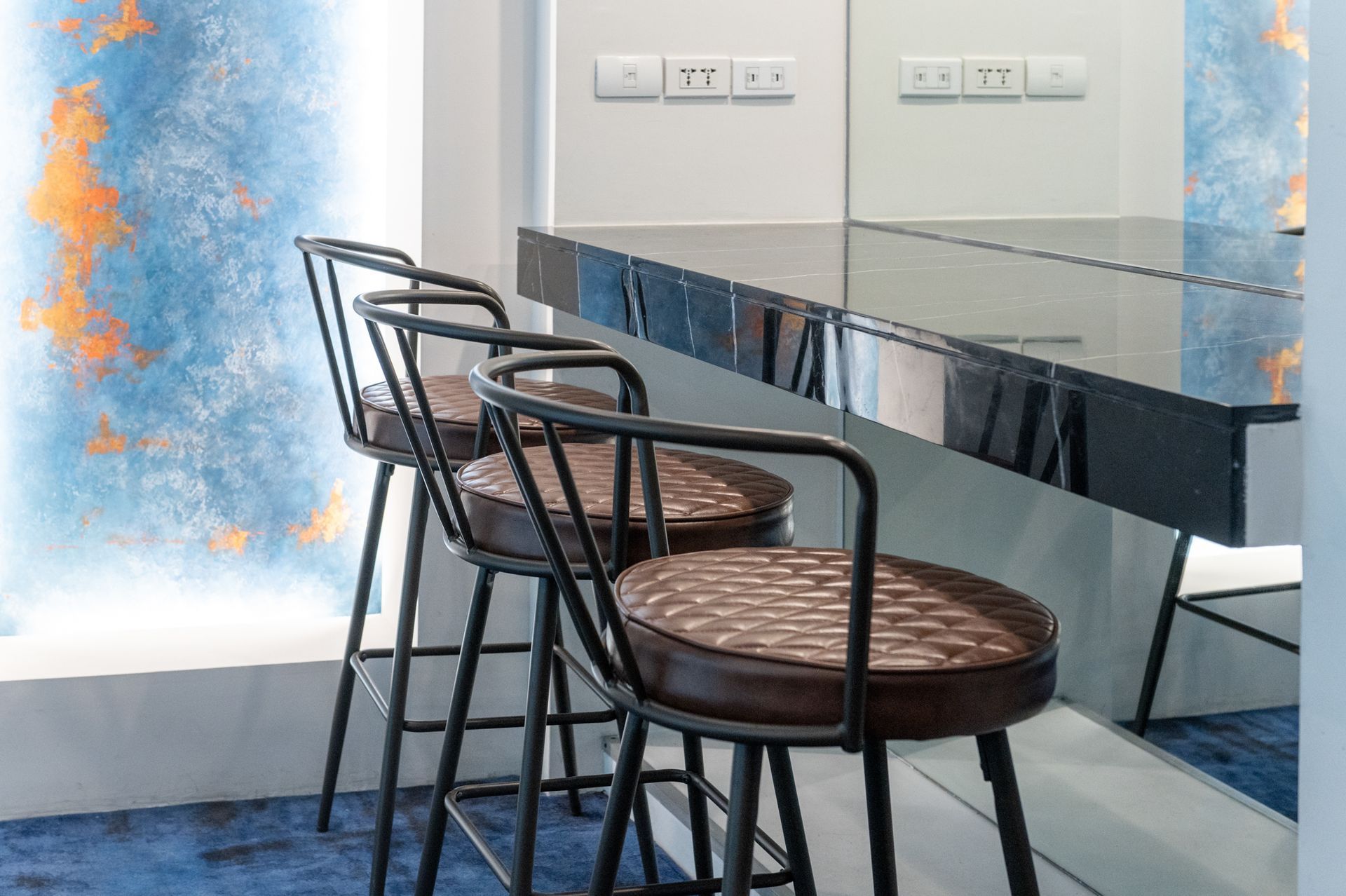 Modern bar stools with leather seats at dark marble counter, Makati