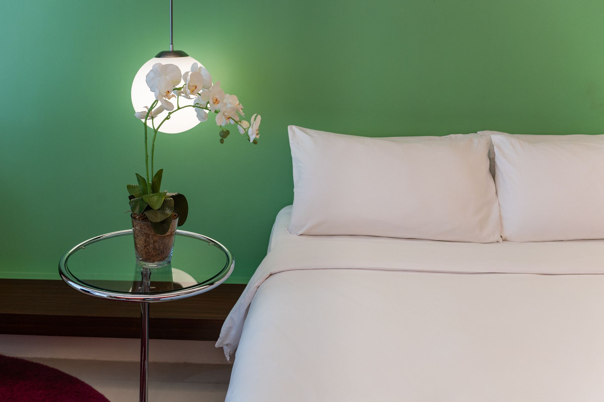 A bedroom with a bed and a table with a plant on it