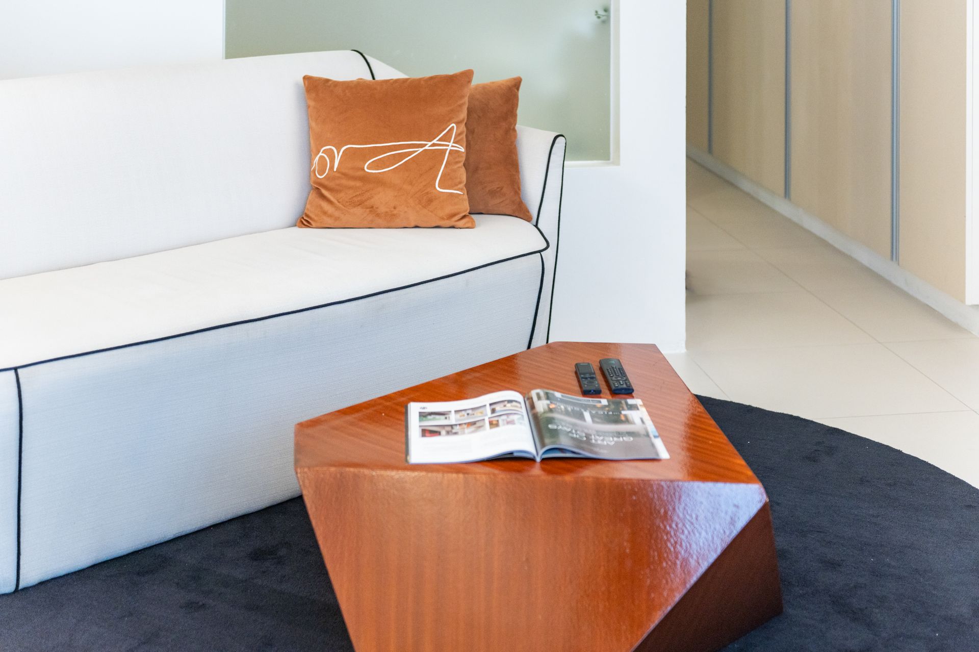 A brown pillow with the letter a on it sits on a white couch