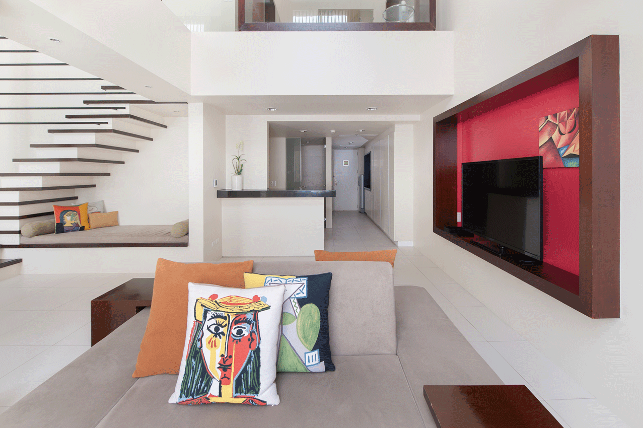 Modern living area in Picasso serviced residence with red accent wall and decorative pillows