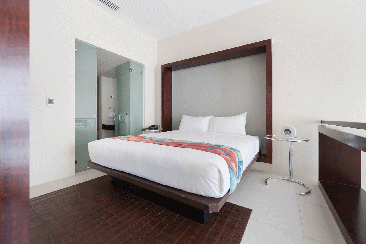 A hotel room with a king size bed and a table.