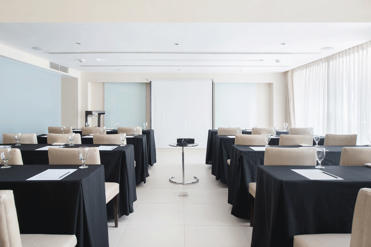 A versatile conference room with tables and chairs and a projector screen at The Picasso.