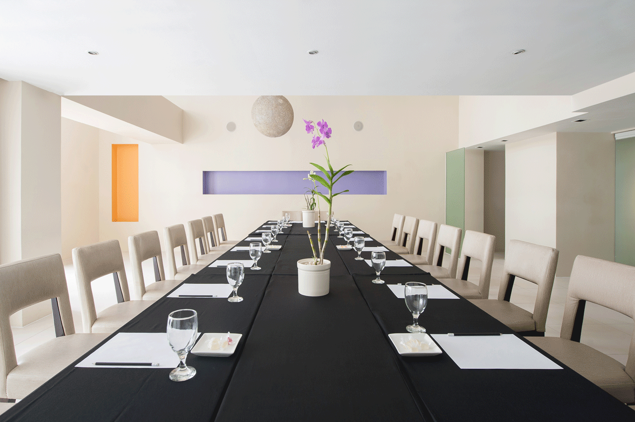 A conference room with tables , chairs and a large screen at The Picasso.