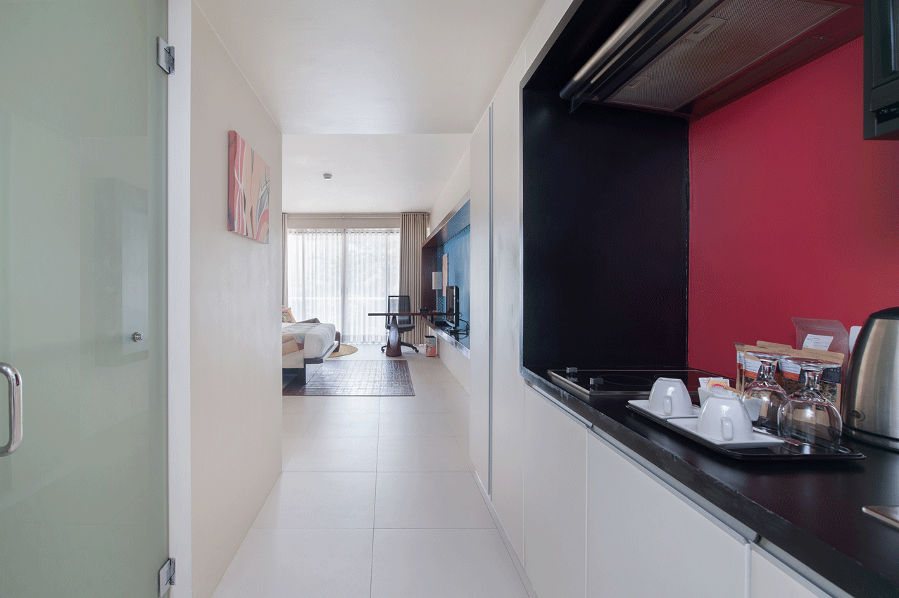 A kitchen in The Picasso hotel room with a refrigerator, stovetop, and microwave.