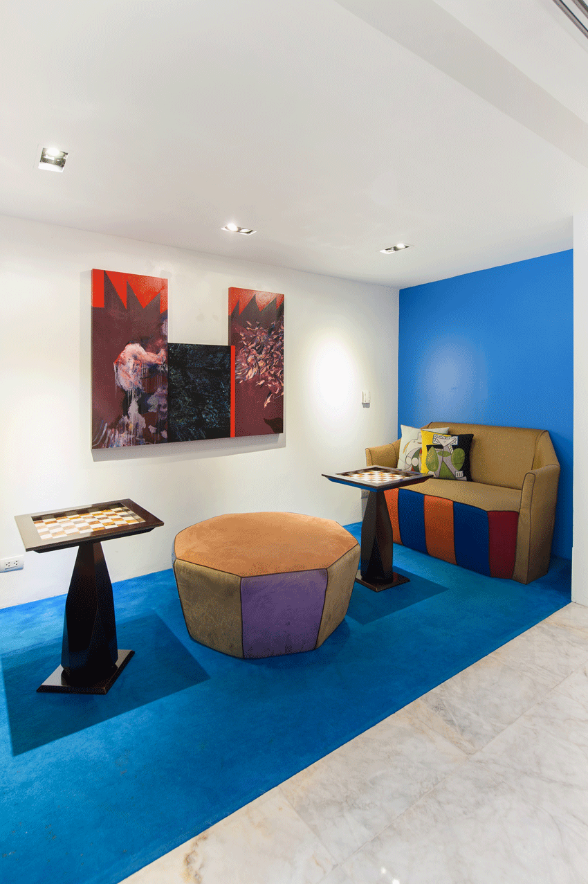 Picasso's lobby with a couch , ottoman , table and paintings on the wall.