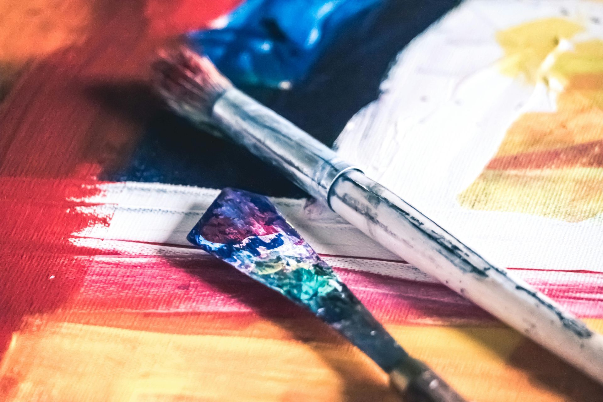 A brush and spatula are sitting on top of a painting.