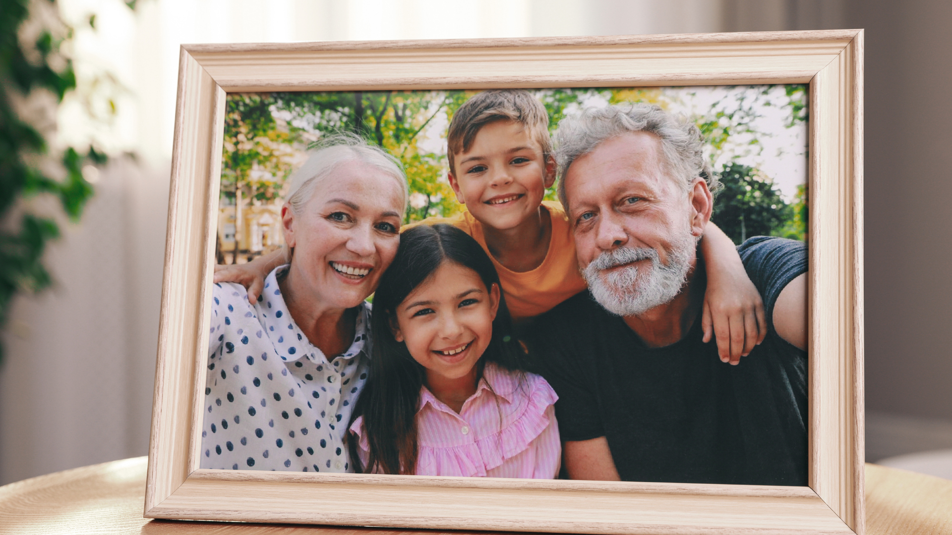 Image of a light brown wooden picture frame with a photo inside of it of grandparents with grandkids