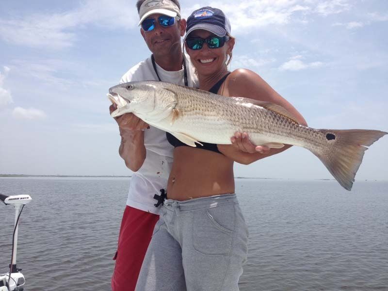 A man and a woman on a boat holding a large fish