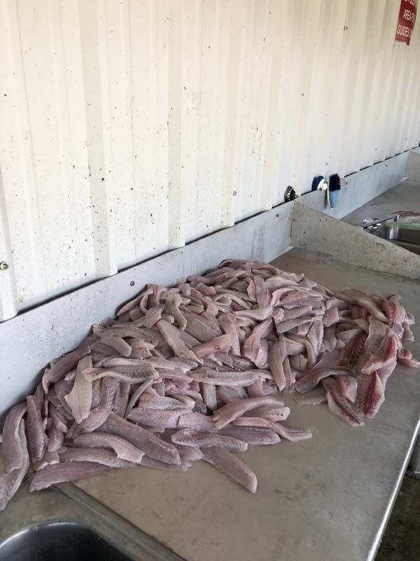 A pile of meat is sitting on a cutting board next to a sink.