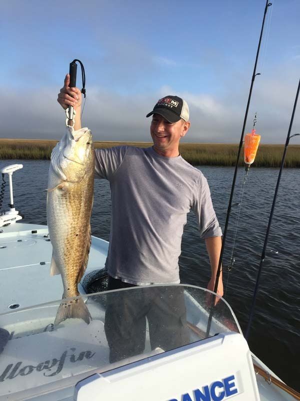 A man is holding a large fish on a boat.