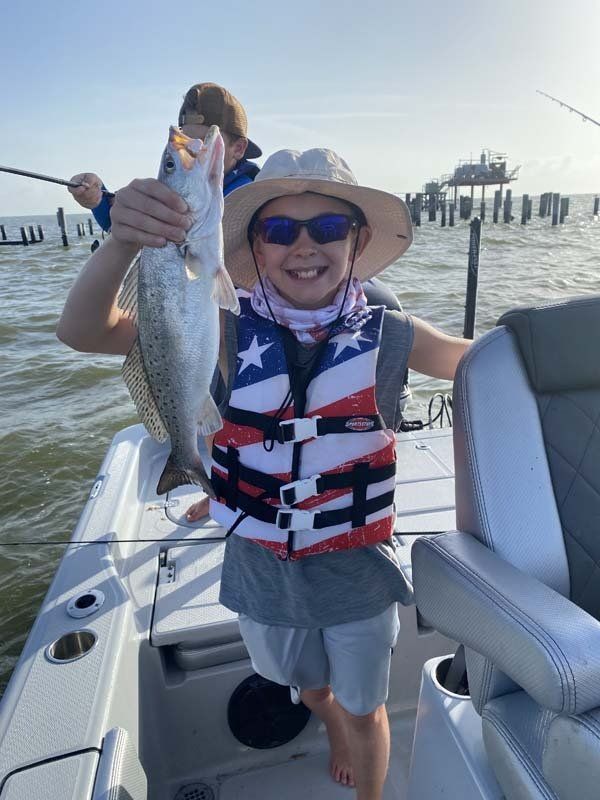 A young boy is holding a fish on a boat.