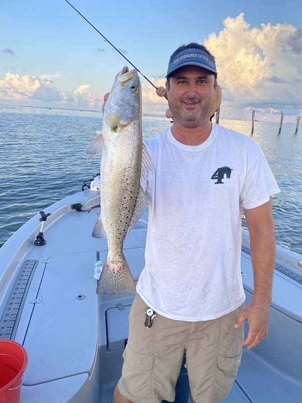 A man is holding a large fish on a boat.