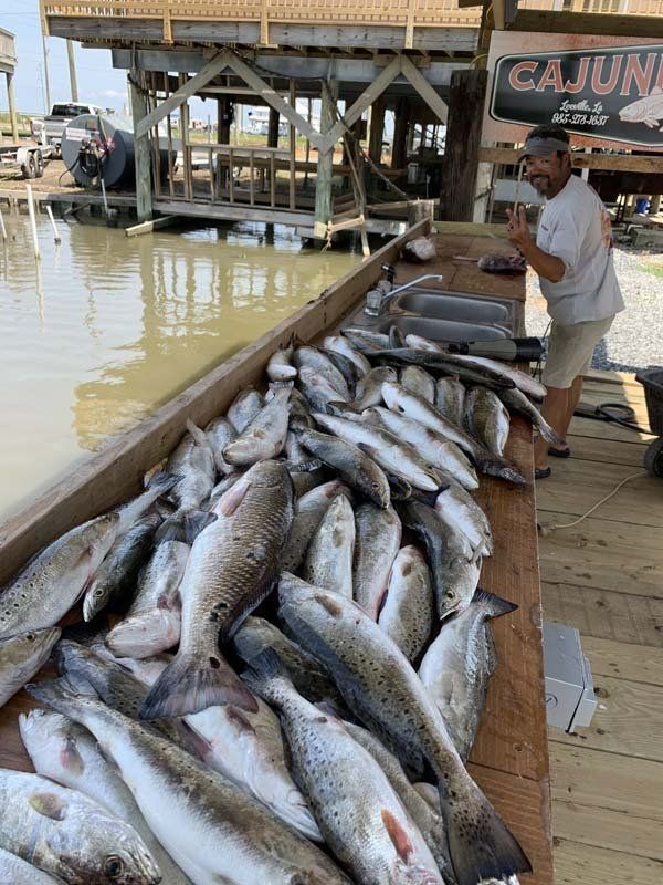 A man is standing next to a table filled with fish.