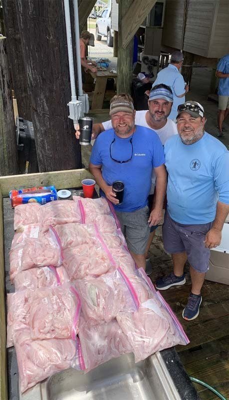 A group of men are standing next to bags of shrimp.